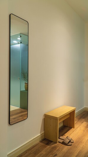 A hallway with a wooden bench, a mirror, and a pair of slippers on the floor. - Near Ben Thanh Market: 2 Beds Apt by D Haus with Netflix (Thành phố Hồ Chí Minh)