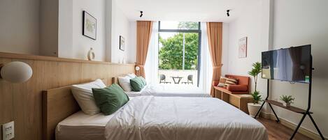 Een moderne hotelkamer met een groot bed, een bureau, een stoel en een televisie op een standaard.