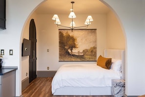 Ein Schlafzimmer mit einem Bett, einer Kandelaber, einem Gemälde und einer Tür.