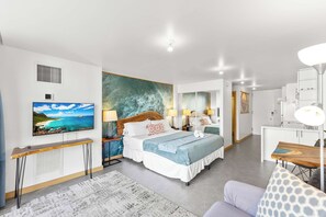 Ein modernes Hotelzimmer mit Bett, Nachttischen, Schreibtisch, Fernseher und angrenzendem Badezimmer.