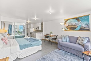 Ein modernes Hotelzimmer mit Bett, Sofa, Esstisch und Küchenzeile.
