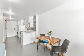 Eine moderne Küche mit weißen Schränken, einer eingebauten Mikrowelle und einer gefliesten Spritzschutzleiste.