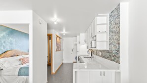 A modern hotel room with a large bed, a bathroom, and a kitchenette. - Modern Designer Studio in Waikiki near Ala Moana (Honolulu)