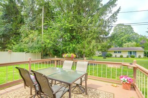 A covered patio with a glass table and chairs, surrounded by a wooden deck and a metal railing. - Group-Friendly Rambler w/ Fenced Backyard & Deck (Toledo)