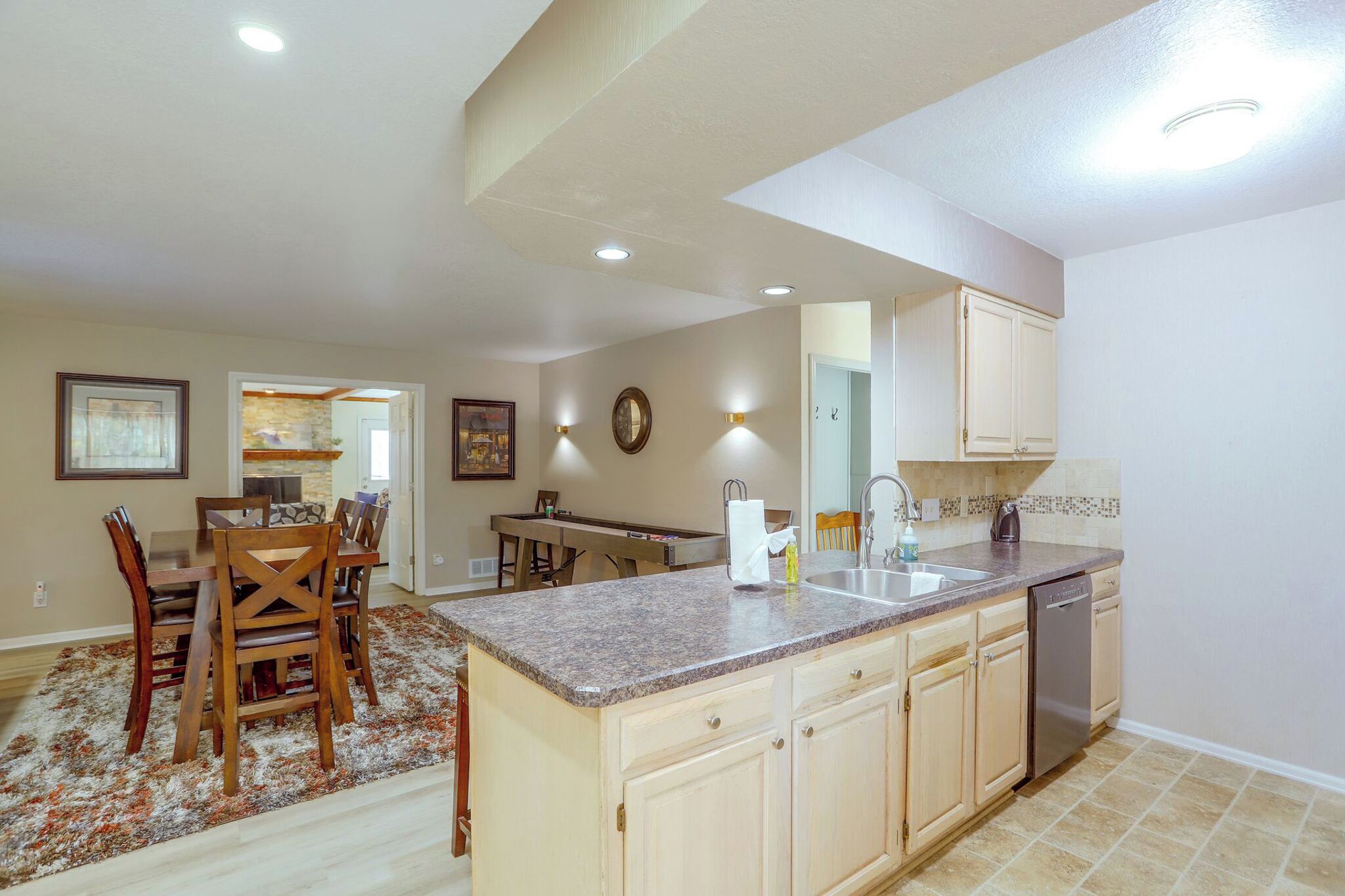 A spacious kitchen with a central island, wooden cabinets, and a built-in dishwasher.