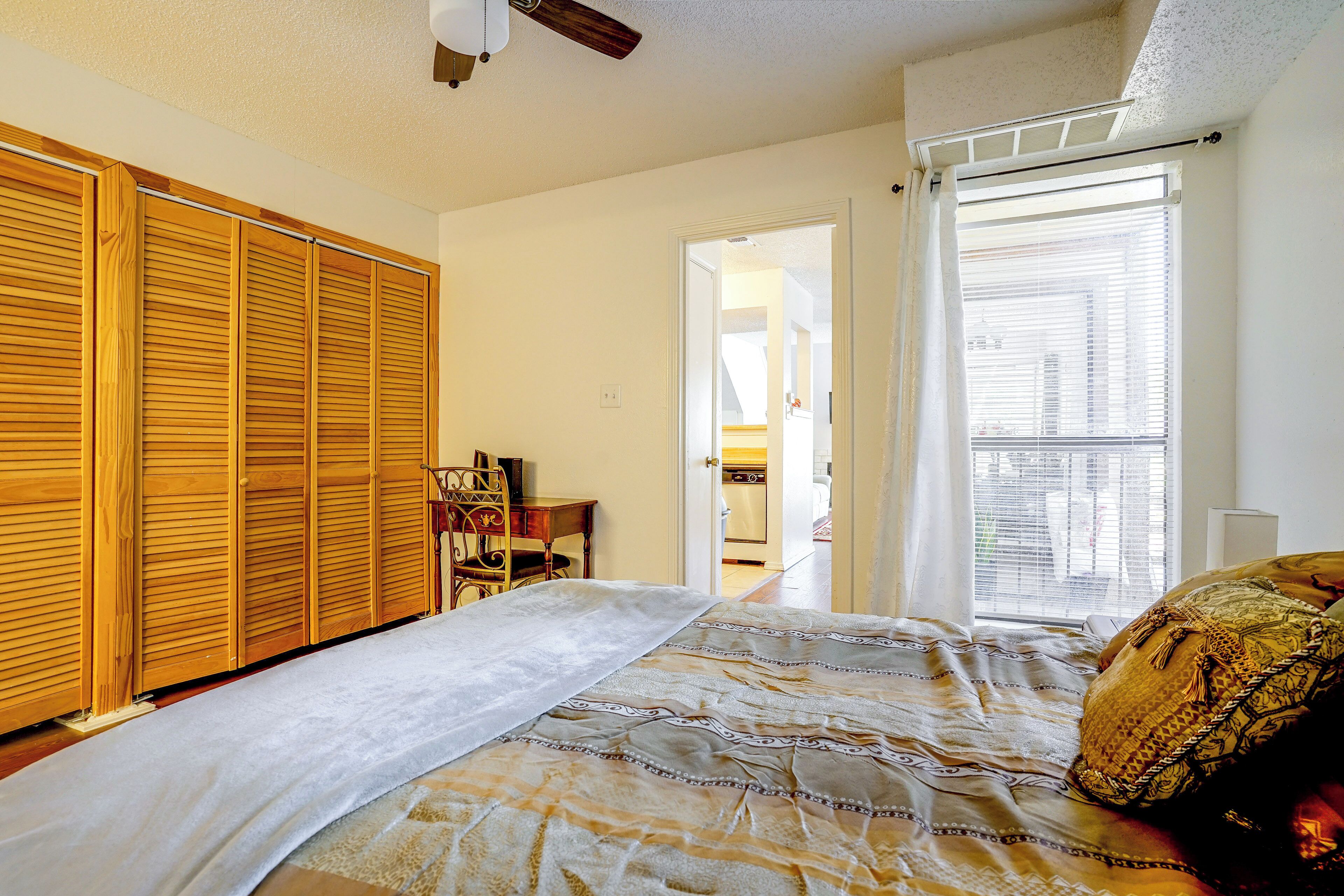 Une chambre à coucher comprenant un lit, une armoire, un bureau avec une chaise et une fenêtre avec des stores.