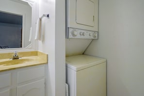 Un lavadero pequeño con lavadora, secadora y lavabo.