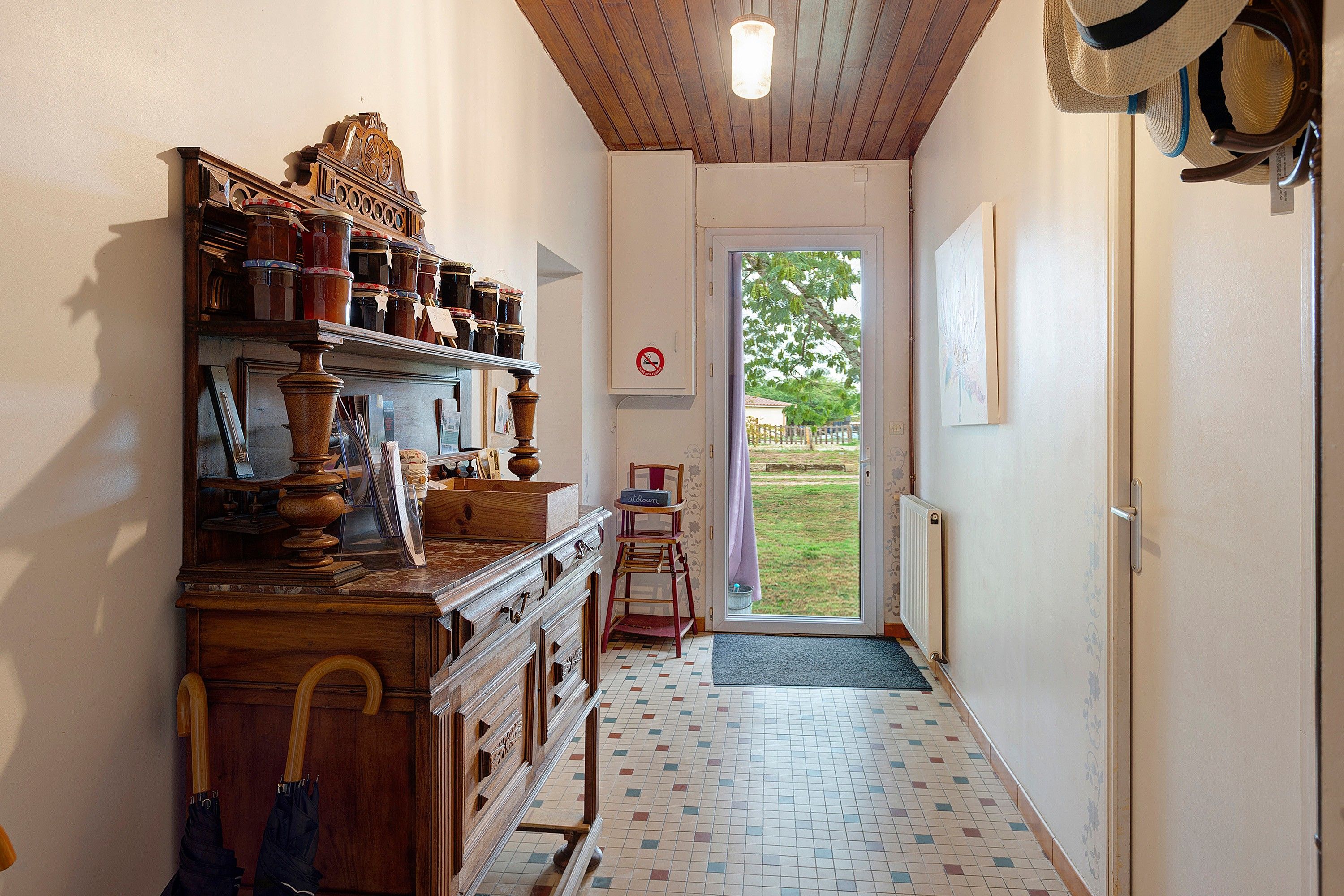 Een gang met een houten kast, een radiator en een deur naar buiten.