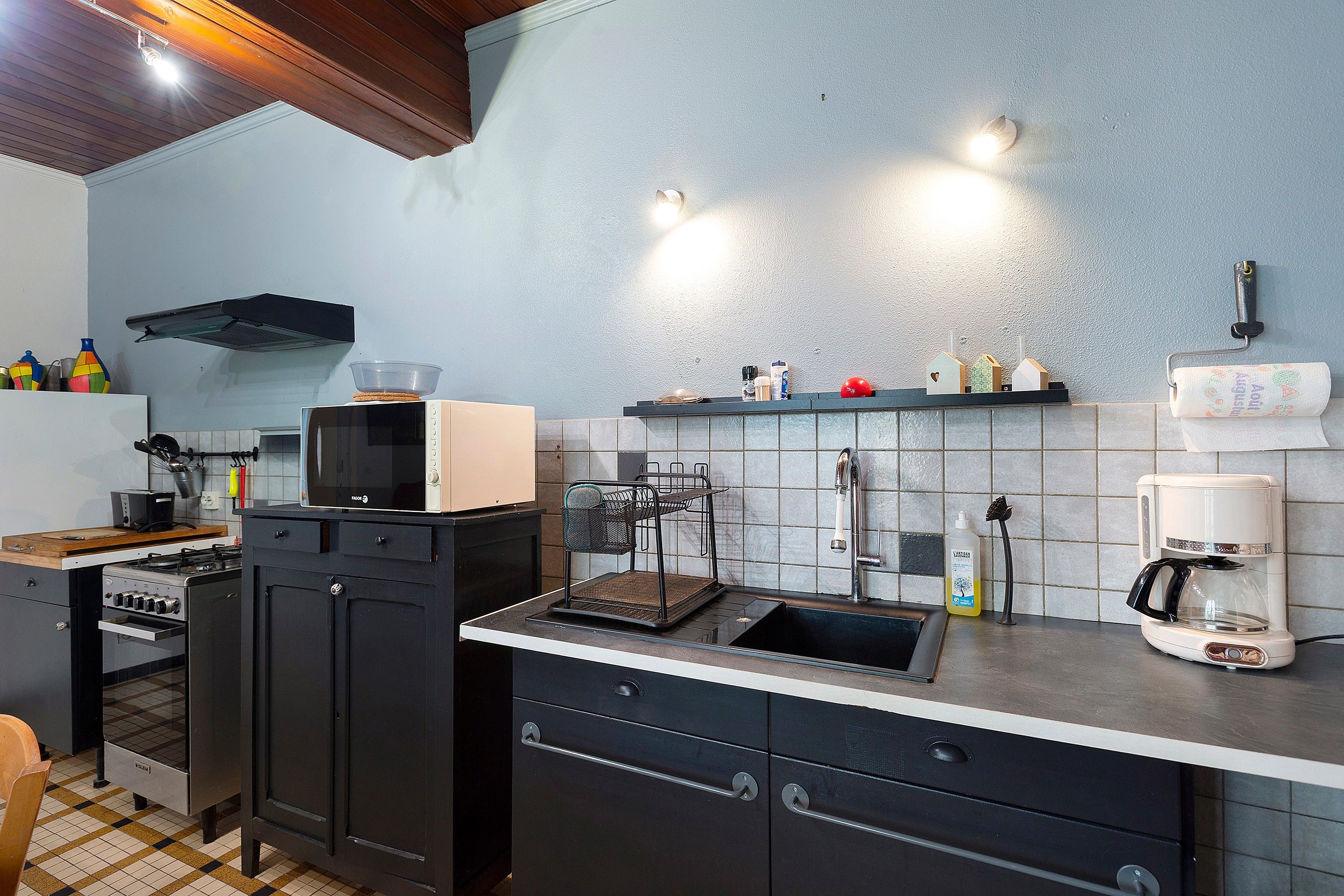 A compact kitchen with a microwave, stove, sink, and various kitchen utensils.
