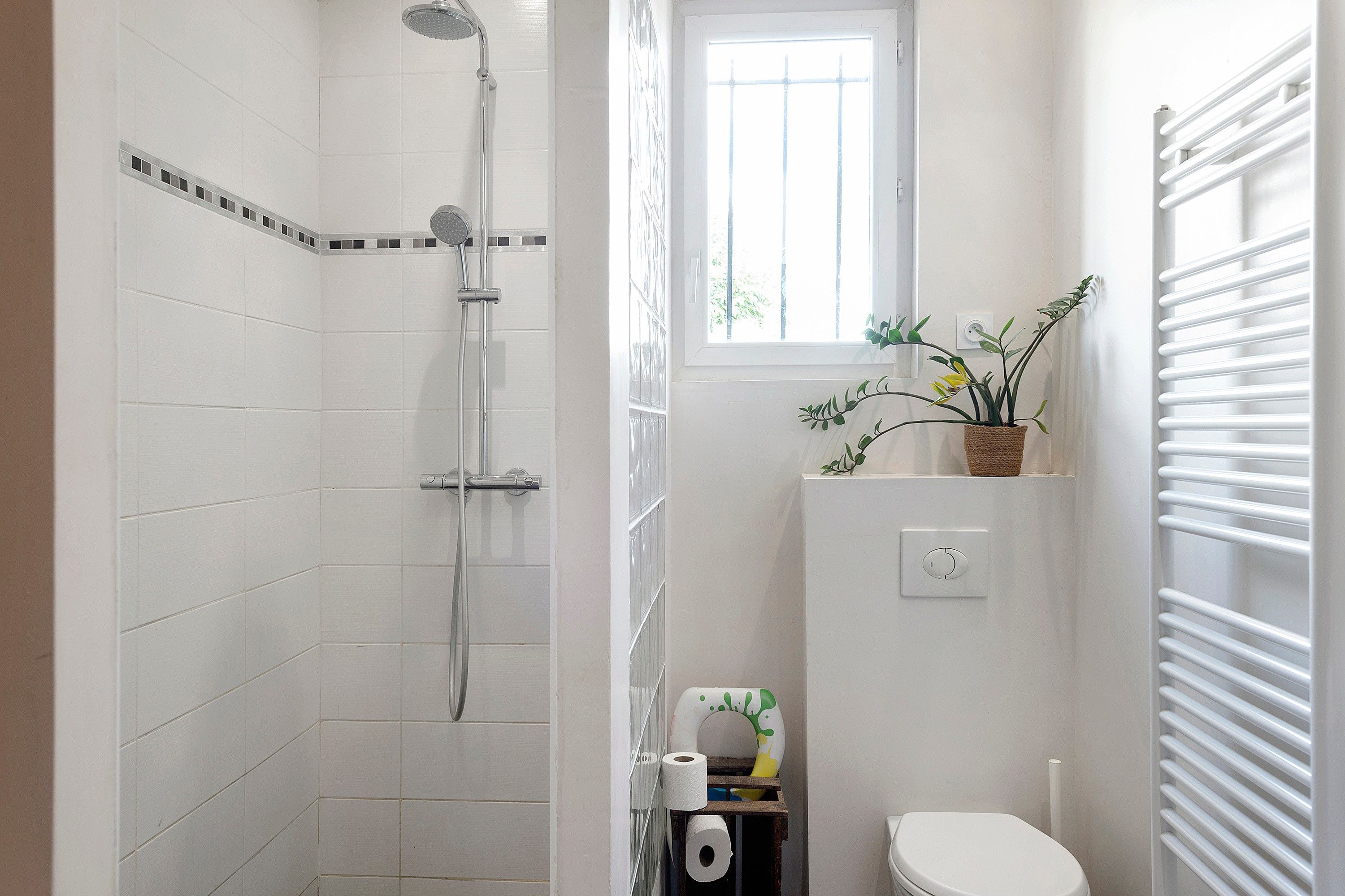 Et badeværelse med bruser, toilet og et vindue.
