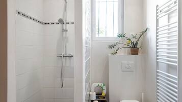 Et badeværelse med bruser, toilet og et vindue.