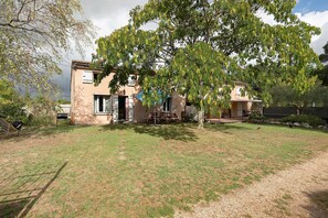 A two-story house with a patio area, a small garden, and a tree in front. - Gîte de Bossuet – Wi-Fi, Garden & Air Conditioning near Bordeaux & Atlantic Coast (Saint-Denis-de-Pile)