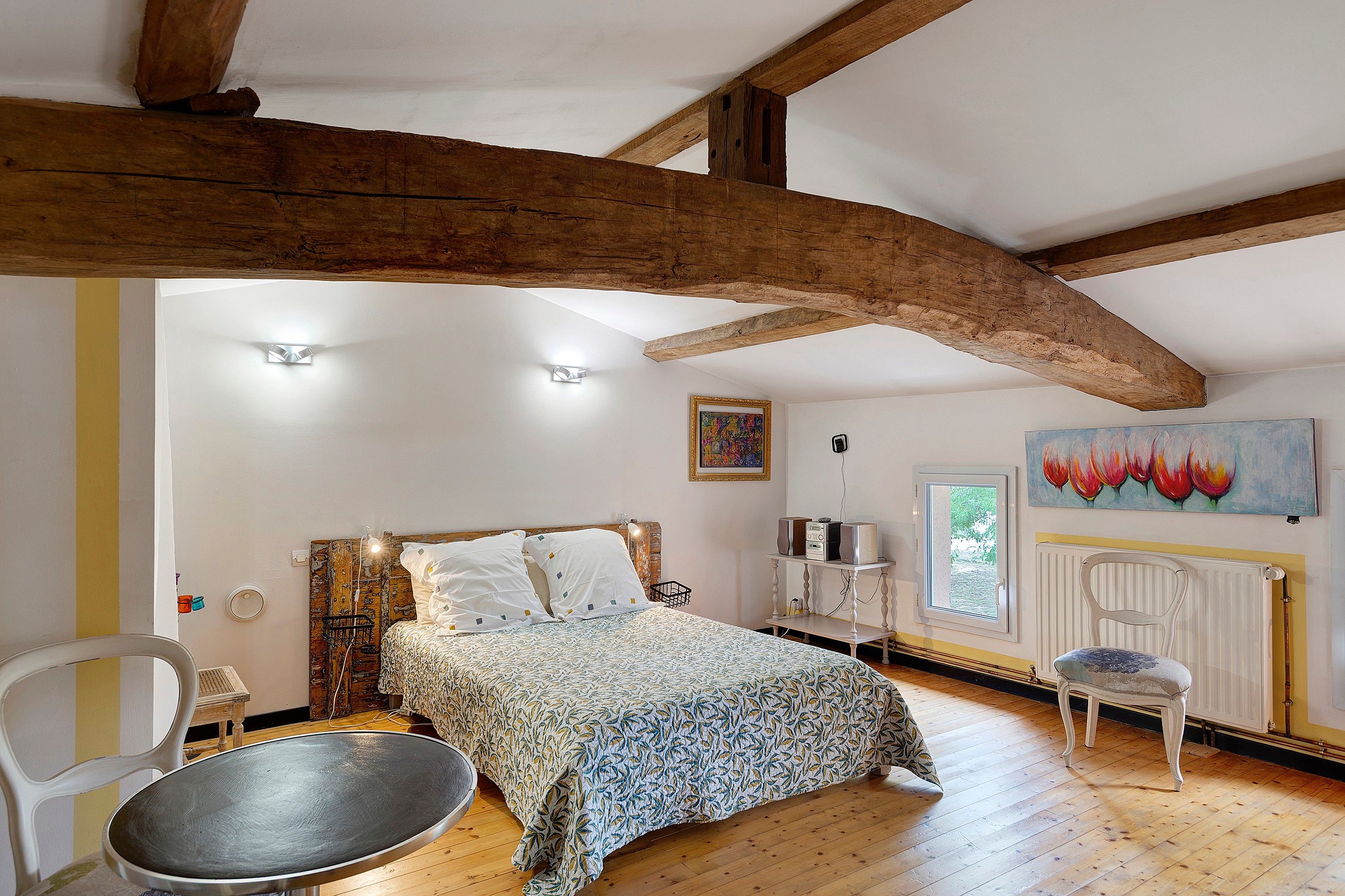 Un dormitorio con cama, una silla, un radiador y un cuadro en la pared.