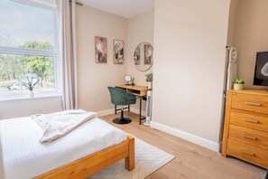 A bedroom with a bed, a desk, a chair, a dresser, and a window with curtains. - Bright & Stylish 1BR Flat near Preston City Centre (Preston)