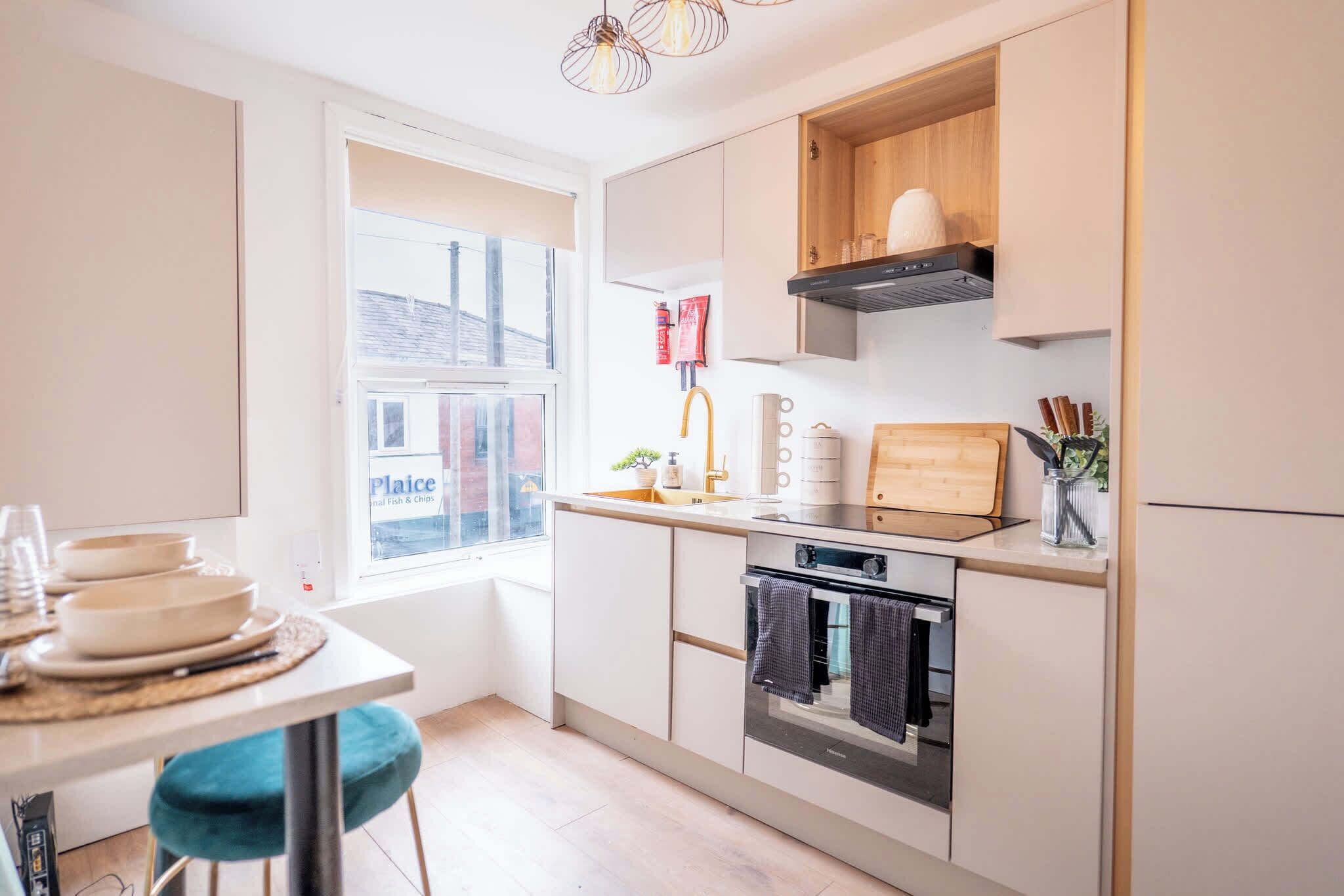 Une cuisine moderne dotée d’une fenêtre, d’un four encastré et d’un coin repas avec une table et des chaises.