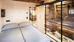 A room with a bed, a wooden wall, and a large window. - Elegant Apartment in a Converted Stable (Matrei in Osttirol)