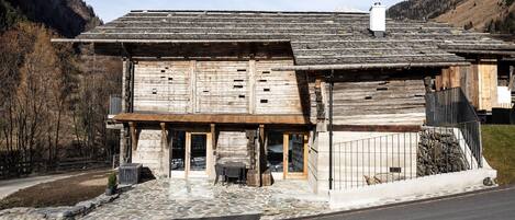 A rustic wooden building with a stone foundation, a wooden porch, and a stone staircase leading to the entrance.