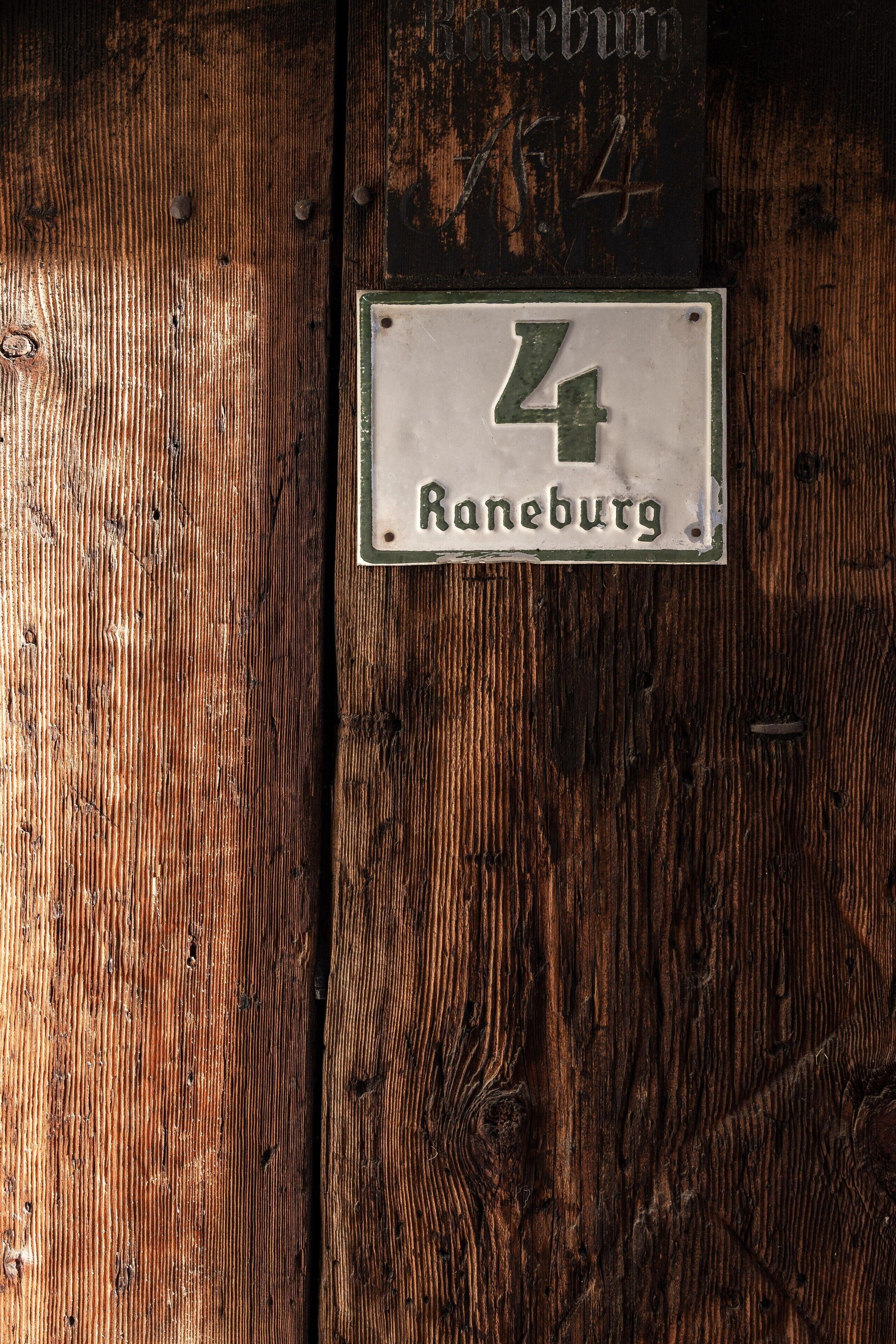 Parede de madeira com uma placa de metal exibindo o número 4 e a palavra 'Raneburg'.