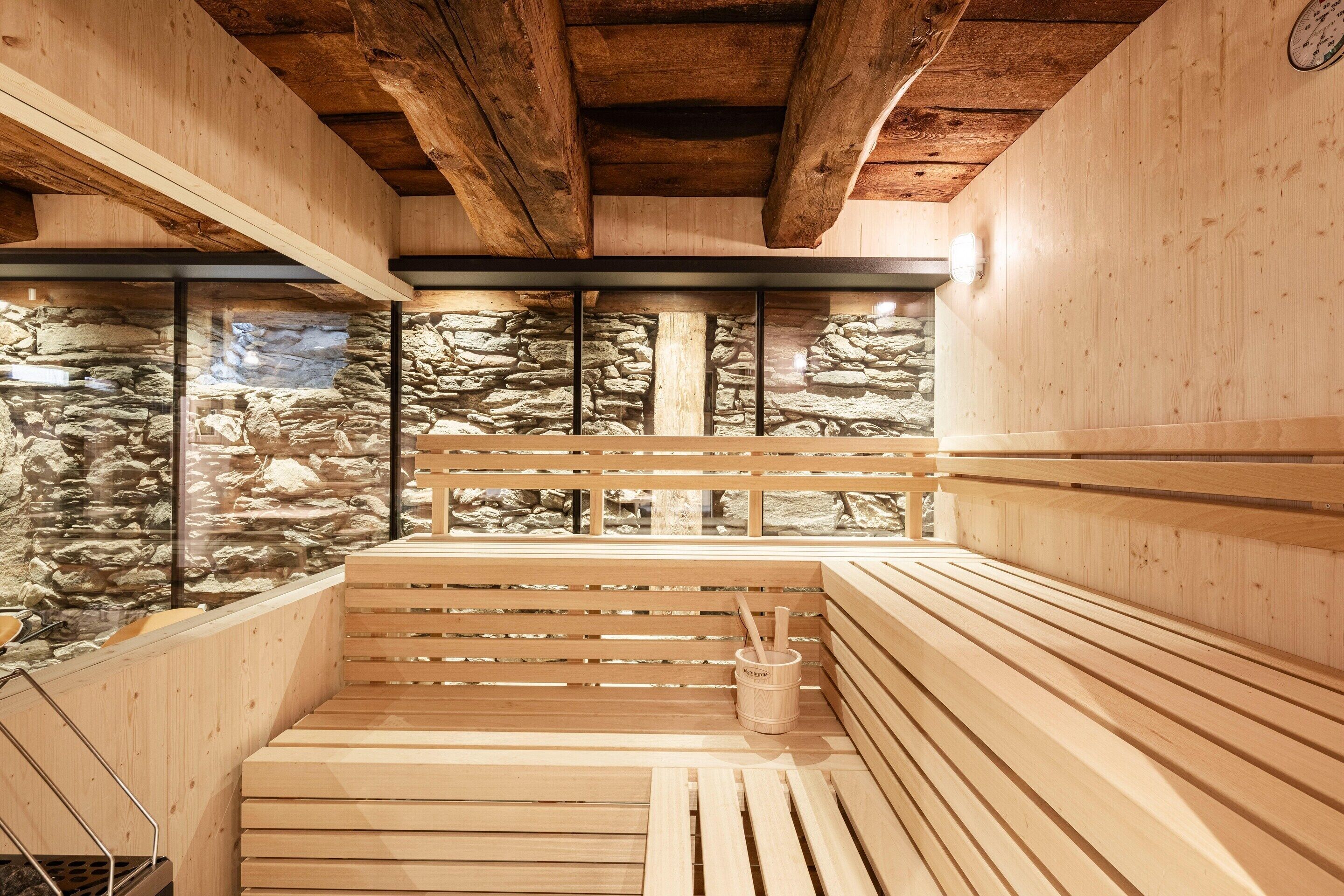 A sauna with wooden benches, stone walls, and a wooden ceiling.