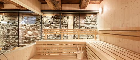 Una sauna con bancos de madera, paredes de piedra y techo de madera.