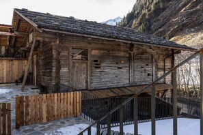 A rustic wooden cabin with a steep roof, surrounded by snow and mountains. - Elegant Apartment in a Converted Stable (Matrei in Osttirol)