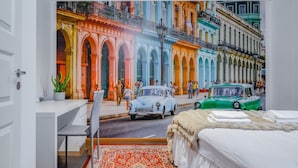 Une chambre à coucher avec une fresque représentant une scène de rue, un lit, un bureau et une chaise.