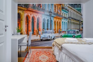A bedroom with a mural of a street scene, a bed, a desk, and a chair.