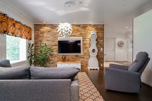 Ein modernes Wohnzimmer mit einem Flachbildfernseher, einer Wanduhr und zwei grauen Sofas.