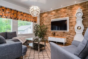 A modern living room with a stone wall, a large TV, and a decorative clock.