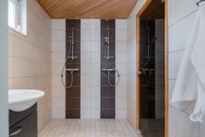 A bathroom with a shower, a sink, and a towel rack.