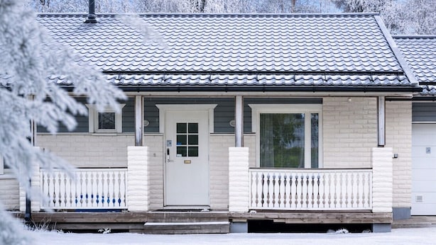 A two-story building with a covered porch, a front door, and a window.
