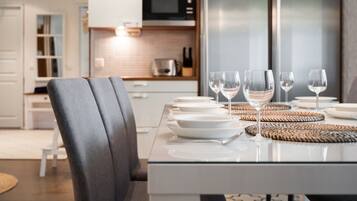 A modern kitchen with a dining table set for four, including wine glasses and plates.