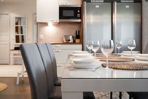 A modern kitchen with a dining table set for four, including wine glasses and plates.