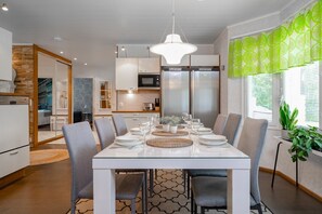 A modern dining area with a white table set for six, surrounded by grey chairs.
