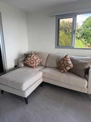 A modern living room with a sectional sofa, a small ottoman, and patterned throw pillows. - Rico Puerto magic spot oeste (Cabrera)