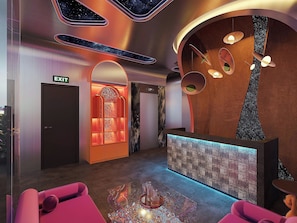 A modern lobby with a reception desk, seating area, and an exit sign.