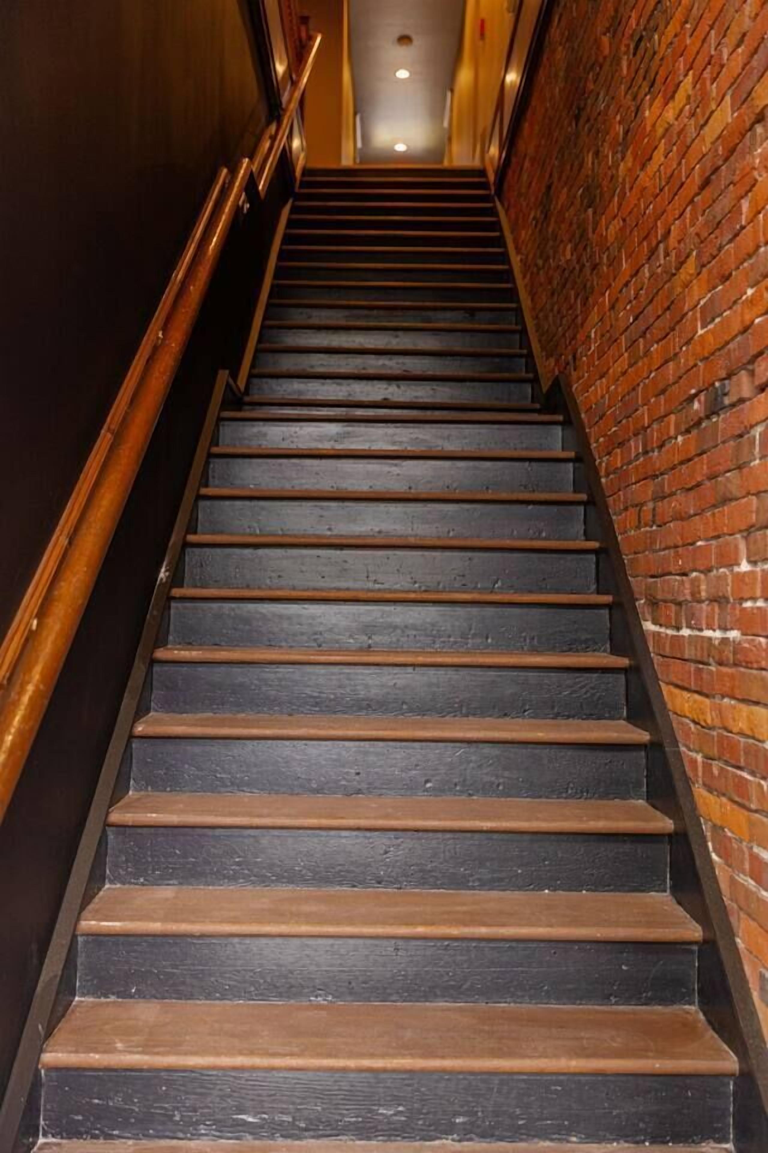 A staircase with wooden steps and a brick wall on one side.