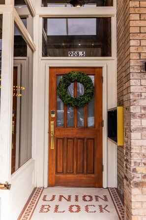 A wooden front door with a wreath, a number '908.5' above it, and a 'UNION BLOCK' mat at the entrance.