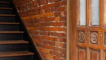 Una escalera con un muro de ladrillo a un lado y una puerta de madera con paneles de vidrio al otro.