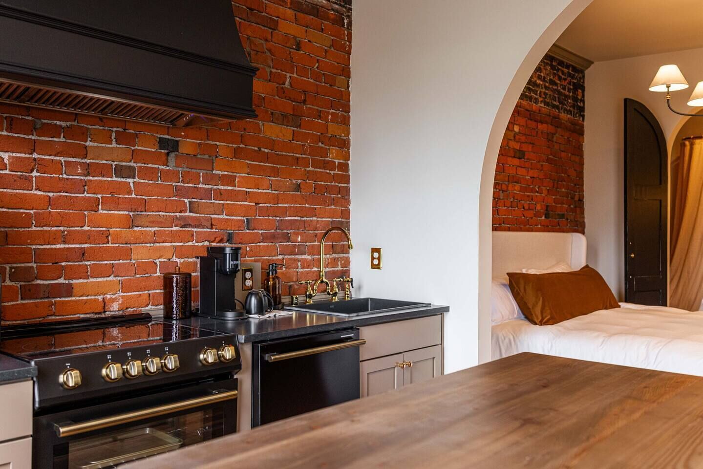 Una cocina con pared de ladrillo, estufa y lavabo.
