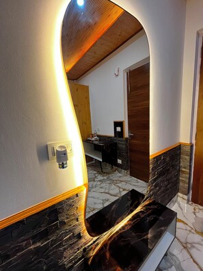 Un baño moderno con un diseño curvo único, encimera de mármol y techo de madera.