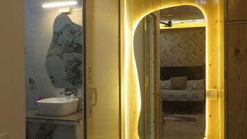 Un baño con lavamanos de mármol, paredes de madera y un espejo con un marco curvo singular.