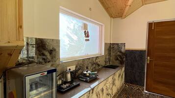 A kitchen with a marble countertop, a built-in microwave, and a window with a view of trees.