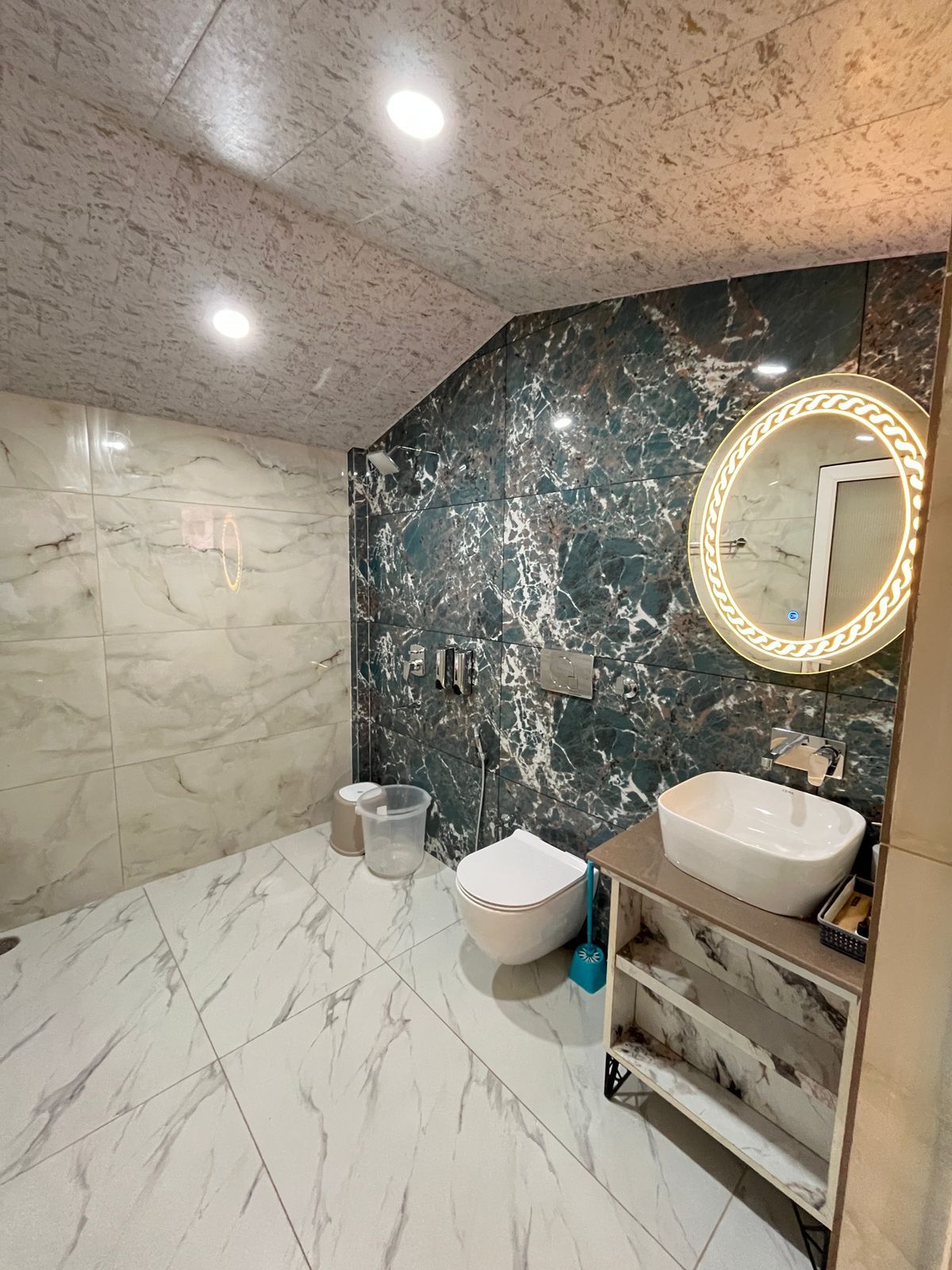 A bathroom with a marble floor, a white toilet, a white sink, and a vanity with a mirror.