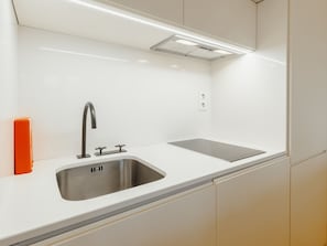 A modern kitchen with a stainless steel sink, a faucet, and a built-in stove. - Apartment  by Interhome (Porto)