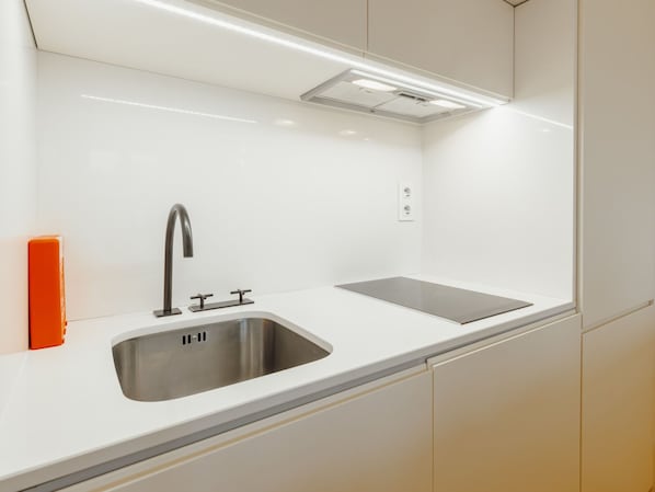 Une cuisine moderne dotée d’un évier en acier inoxydable, d’un robinet et d’une cuisinière intégrée.
