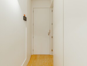 A narrow hallway with a wooden floor leading to a white door. - Apartment  by Interhome (Porto)