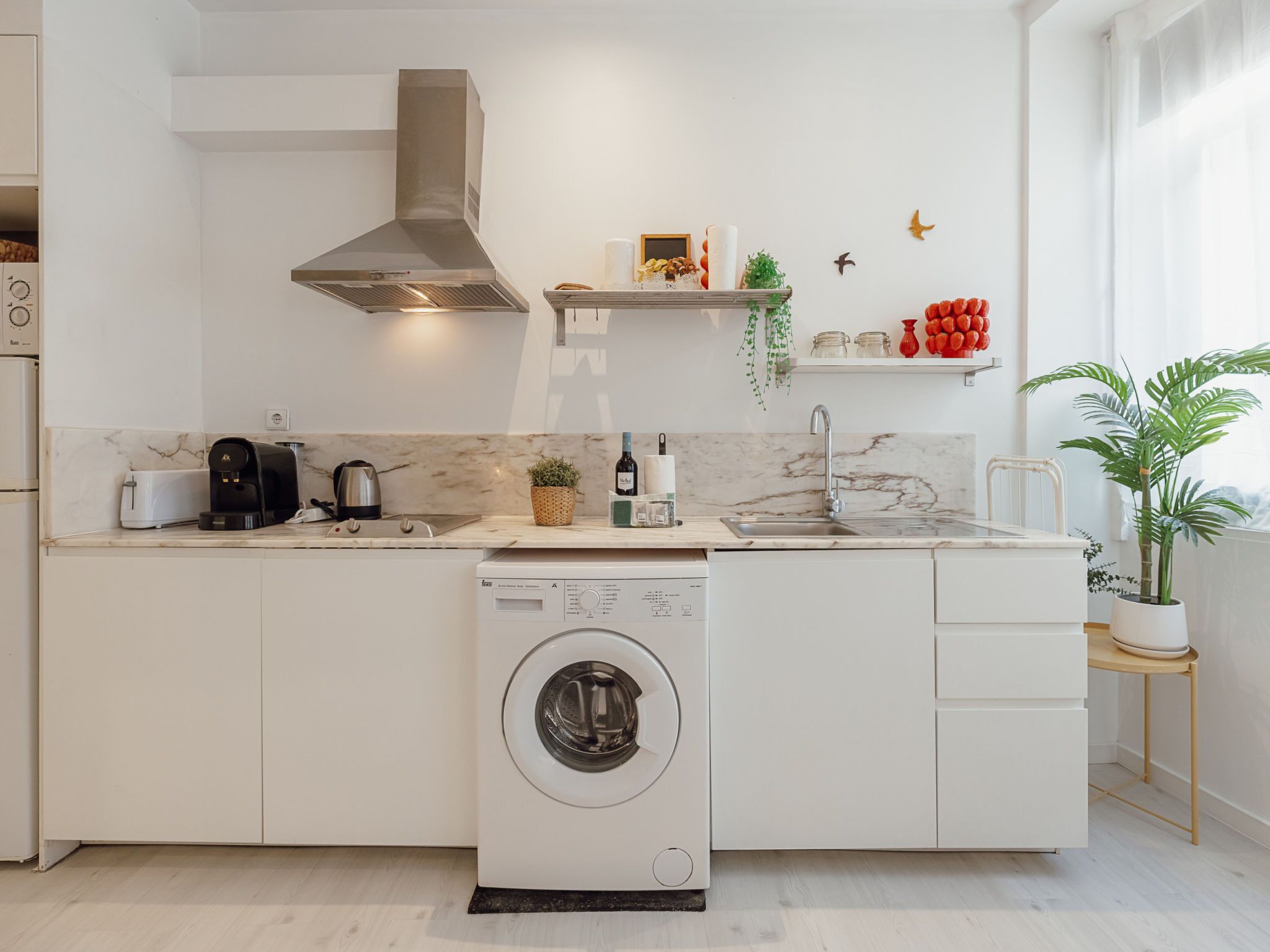 Une cuisine moderne équipée d’un lave-linge intégré, d’une cuisinière et d’un évier.