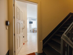 A hotel room entrance with a white door, a staircase, and a view into a dining area with tables and chairs. - Apartment  by Interhome (Porto)