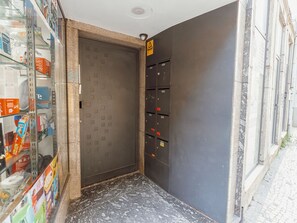 A narrow hallway with a door, a fire alarm, and a set of lockers. - Apartment  by Interhome (Porto)